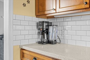 A kitchen with white subway tiles, a coffee maker, and a blender on the counter.