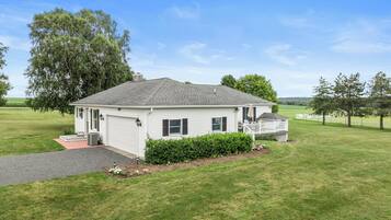 Une maison de plain-pied avec un garage, une véranda et une pelouse bien entretenue.