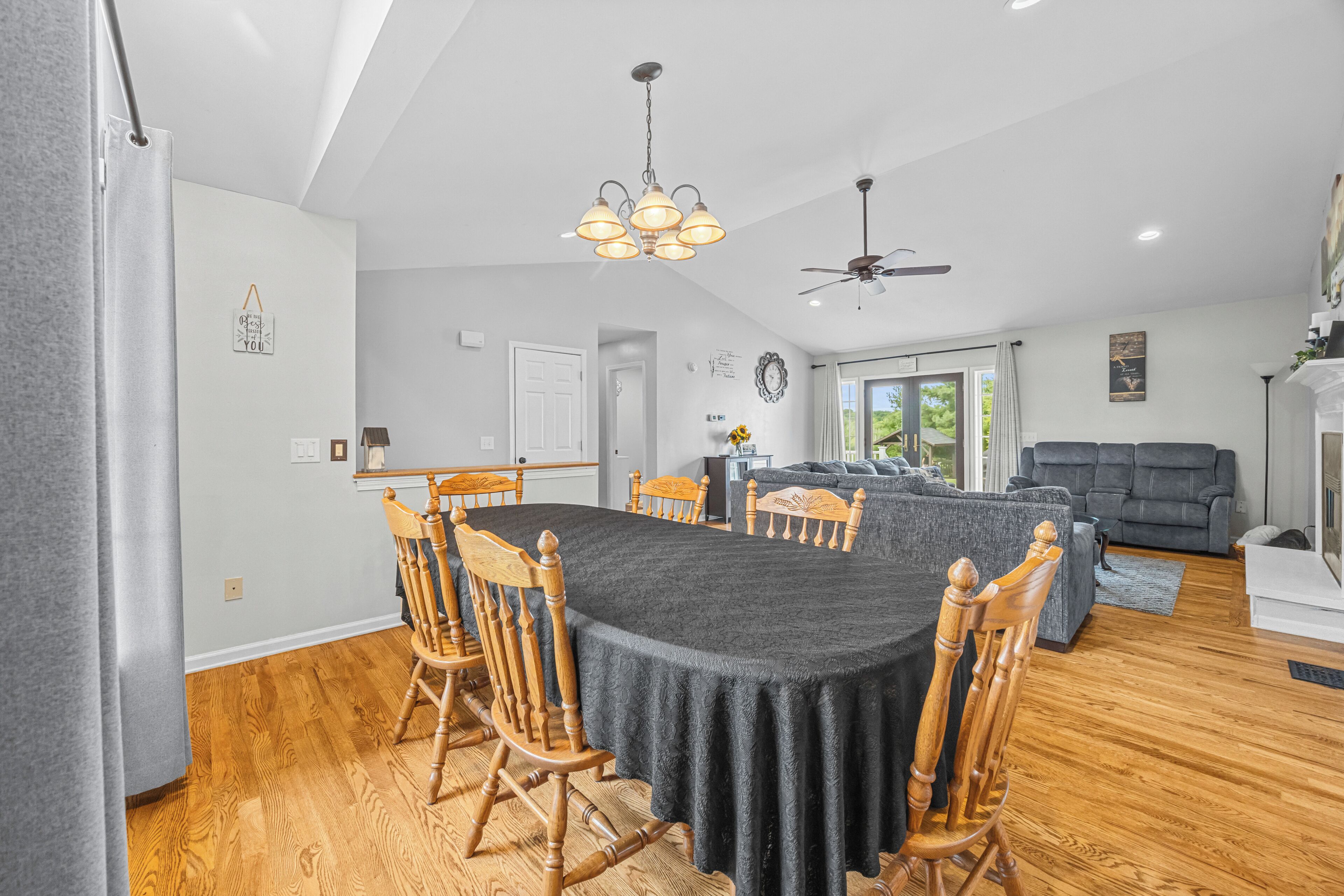 A spacious dining area with a large table surrounded by wooden chairs, a ceiling fan, and a chandelier.