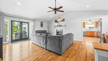 A spacious living room with a grey sectional sofa, a fireplace, and a ceiling fan.