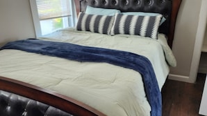 A bedroom with a wooden headboard, a white bedspread, and a blue throw blanket. - Irvington Apartment (Irvington)