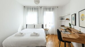 Ein modernes Hotelzimmer mit einem großen Bett, einem Holztisch und einem kleinen Beistelltisch.