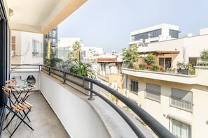 A balcony with a table and chairs, a railing, and a view of neighboring buildings.