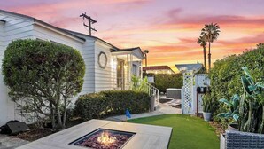 A modern house with a fire pit in the front yard, surrounded by well-maintained hedges and a lawn.
