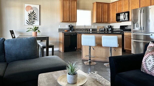 Een moderne keuken met houten kastjes, roestvrijstalen apparatuur en een centraal eiland met barstoelen.