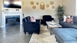 Een woonkamer met een open haard, twee banken, een salontafel en decoratieve wandversieringen.