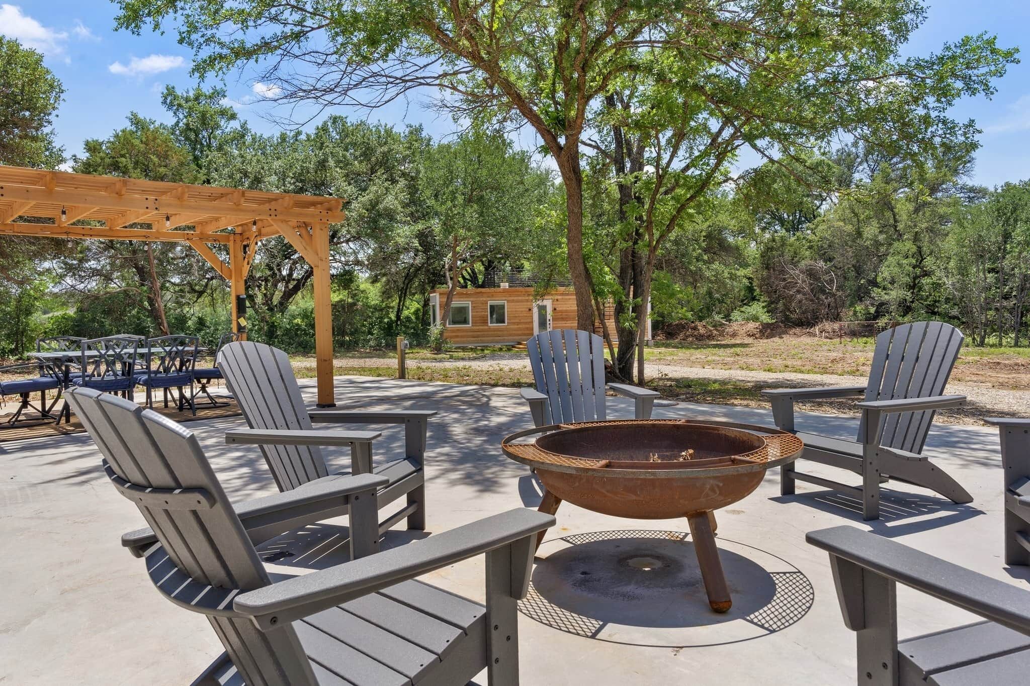 An outdoor seating area with Adirondack chairs and a fire pit.