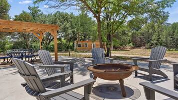 An outdoor seating area with Adirondack chairs and a fire pit.