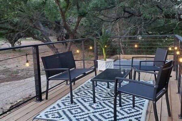 An outdoor seating area with a patterned rug, black chairs, and a table.