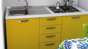 A kitchen with yellow cabinets, a sink, and a stove. - Studio with equipped kitchen - Pisciotta (Pisciotta)