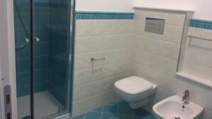 Une salle de bain avec une douche à parois de verre, des toilettes blanches et un lavabo.