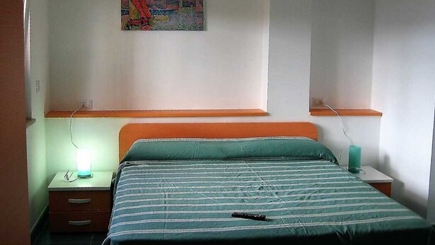 Une chambre à coucher comprenant un lit, une table de chevet, un tableau accroché au mur et une petite table placée près du lit.