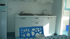 A compact kitchen with white cabinets, a gas stove, and a sink. - Studio apartment Mirtillo (Pisciotta)