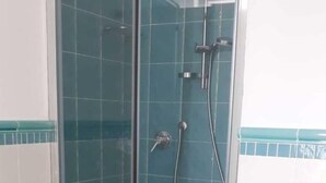 A glass-enclosed shower stall with a tiled floor and walls, a handheld showerhead, and a wall-mounted faucet. - Studio apartment Mirtillo (Pisciotta)
