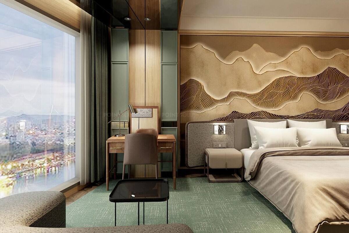 A hotel room with a city view, a desk with a chair, a bed with pillows, and a decorative wall.