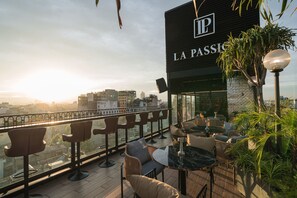 Eine Dachterrasse mit Sitzgelegenheiten im Freien und Blick auf die Stadt, mit einem Schild für "LA PASSION".