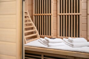 Eine Holzbadewanne mit einer Holzleiter und einem Stapel weißer Handtücher.