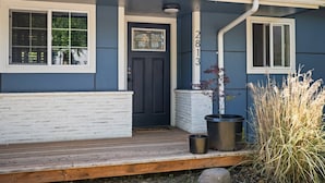 A house with a dark blue exterior, a white front porch, and a black door.