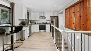 A modern kitchen with white cabinets, stainless steel appliances, and a wooden door.