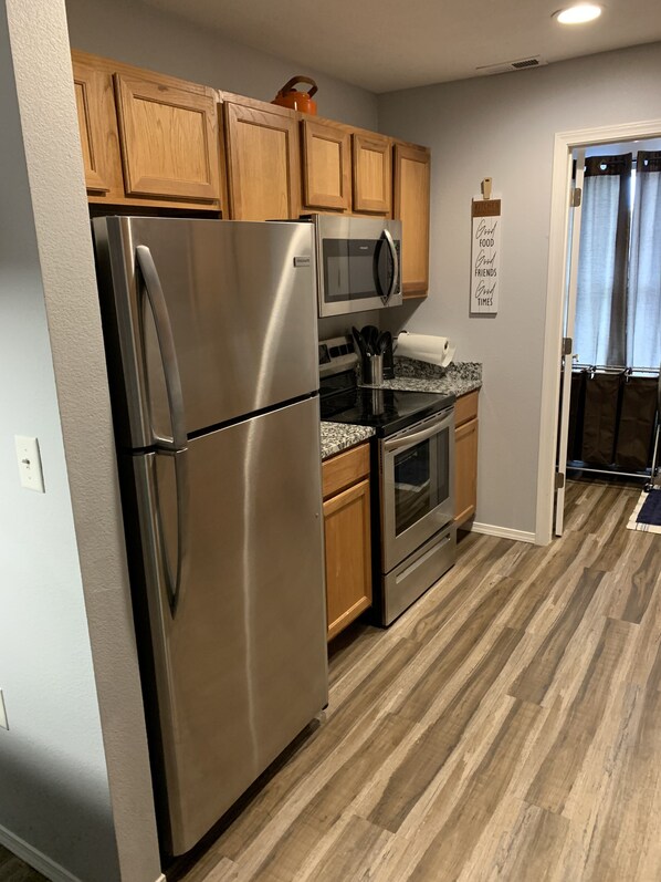 A modern kitchen with stainless steel appliances, wooden cabinets, and a granite countertop.