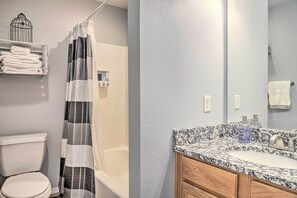 Un baño con inodoro, cortina de ducha y lavabo de encimera de mármol.