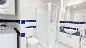 A modern bathroom with a glass-enclosed shower, a toilet, and a sink. - Convenient Studio Steps from AUT University (Auckland)