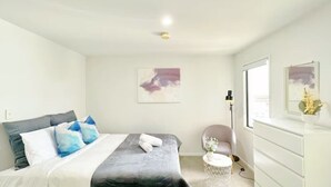 A modern bedroom with a bed, bedside table, chair, dresser, and artwork on the wall. - Convenient Studio Steps from AUT University (Auckland)