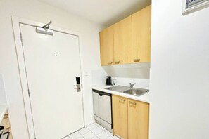 A compact kitchen with white cabinets, a sink, and a coffee maker.
