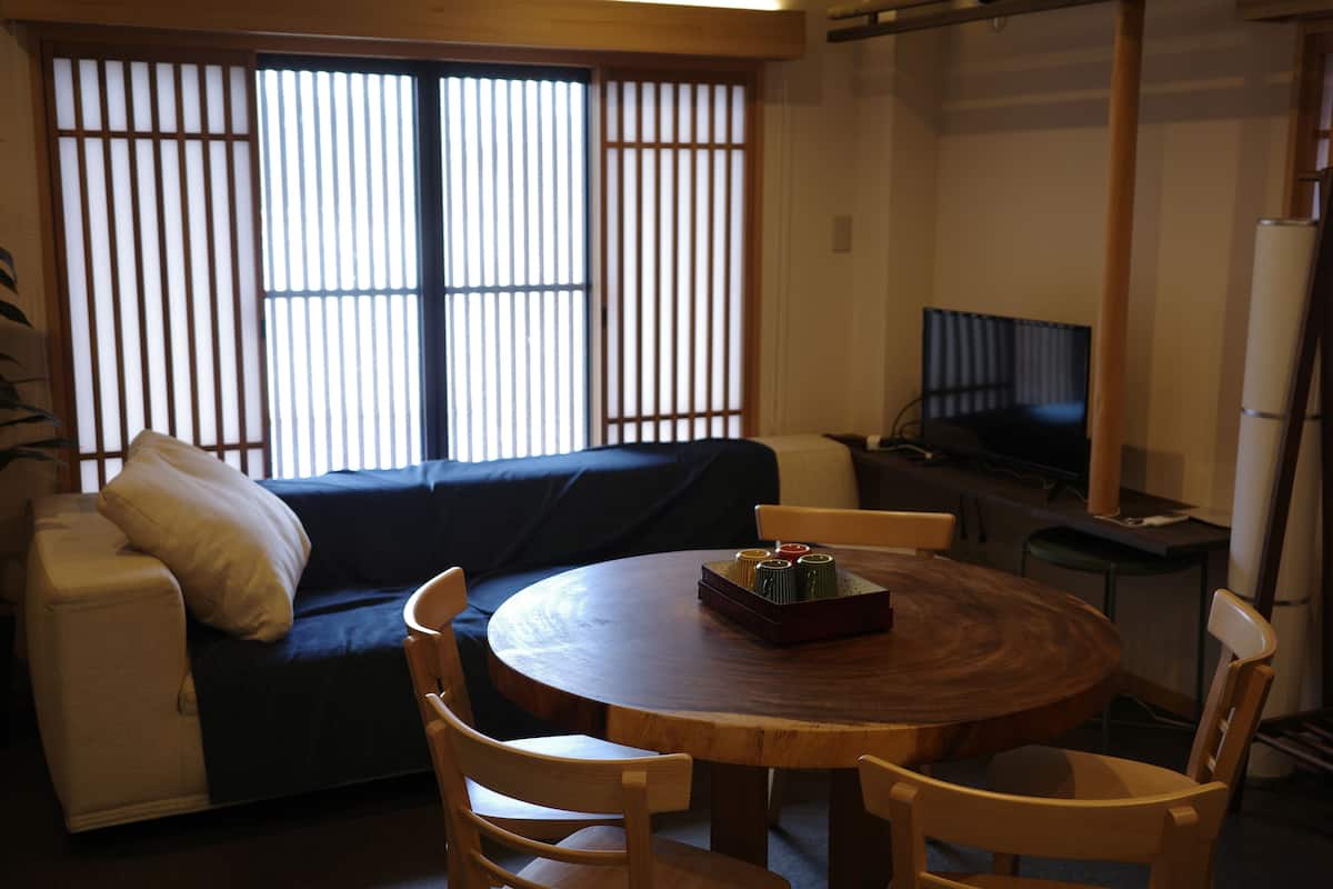 A living room with a sofa, a round wooden table, and a TV.