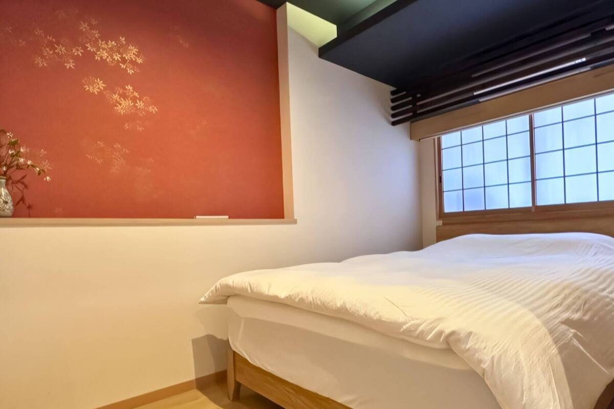 A bedroom with a bed, a window with a grid pattern, and a wall with a decorative pattern.
