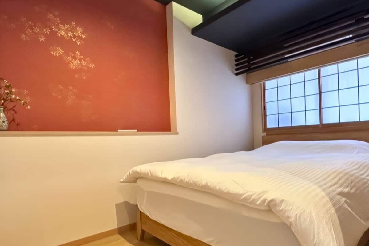 A bedroom with a bed, a window with a grid pattern, and a wall with a decorative pattern.