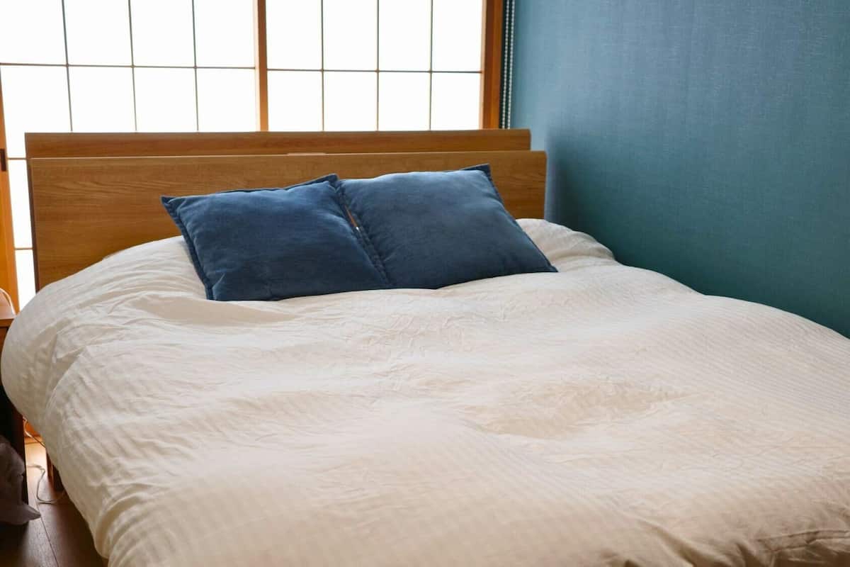 A bed with a wooden headboard, a white bedspread, and two blue pillows.