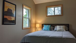A bedroom with a bed, two windows, a nightstand, and a lamp. - Casa Ceylon by Lake Seneca (Dundee)