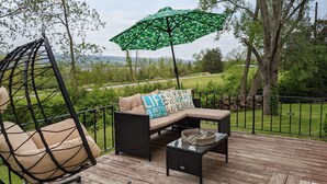 A deck with a hanging chair, a cushioned bench with pillows, and a table. - Casa Ceylon by Lake Seneca (Dundee)