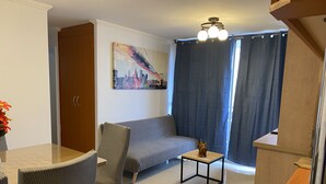 Een moderne woonkamer met een bank, stoelen, een bijzettafeltje en een schilderij aan de muur.