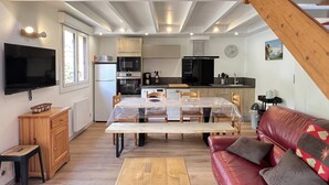 Un espace de vie compact comprenant une cuisine, un coin repas et un canapé en cuir rouge.