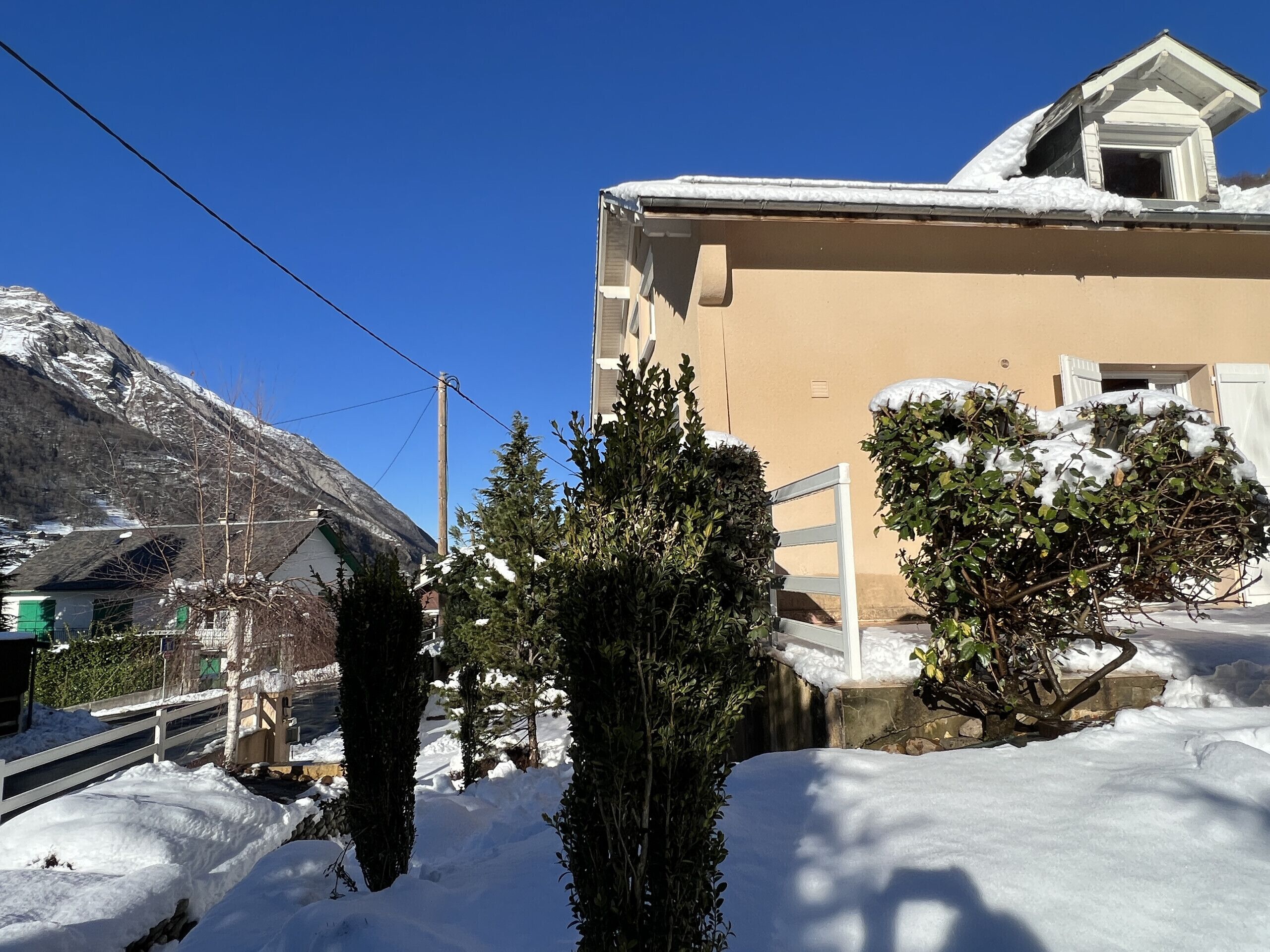 A residential building with a snow-covered roof and a mountain in the background.