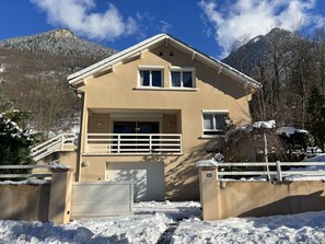 A two-story house with a beige exterior, a front garage, and a balcony.