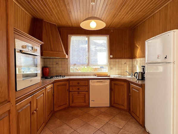 A kitchen with wooden cabinets, a built-in oven, a dishwasher, and a refrigerator.
