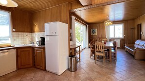 A wooden interior with a kitchen, dining area, and a sofa. - Chalet 5 chambres / 10p (Cauterets)