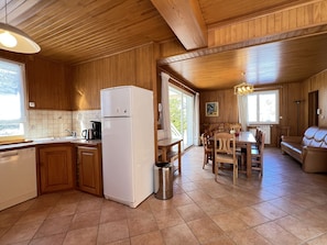 A wooden interior with a kitchen, dining area, and a sofa.