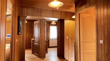A wooden interior hallway with a door leading to a kitchen area.