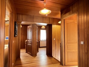 A wooden interior hallway with a door leading to a kitchen area.