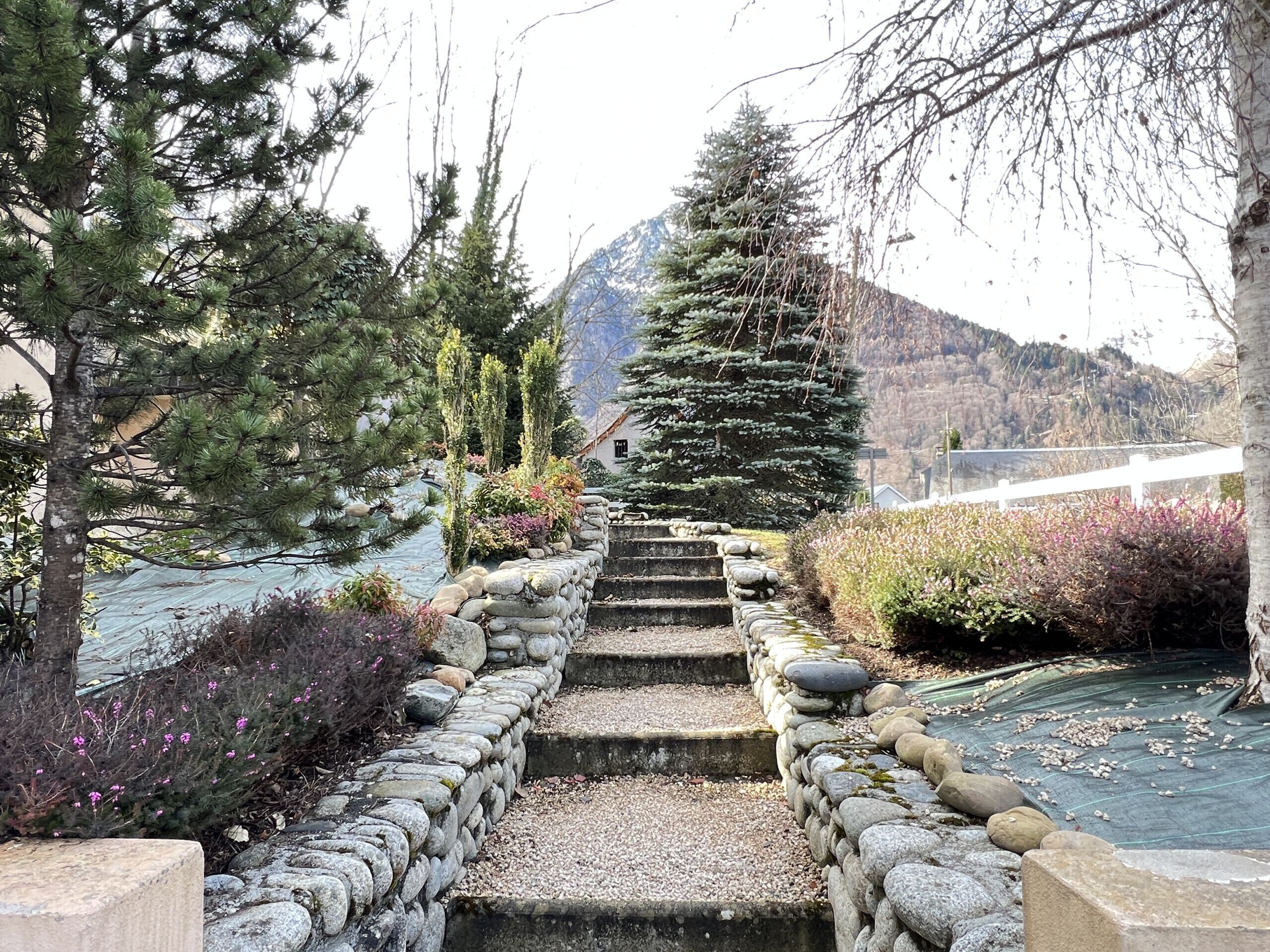 A stone staircase leading to a mountain view, surrounded by trees and shrubs.