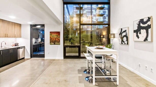A modern kitchen with a dining area, large windows, and artwork on the walls. - Elegant design meets optimal location amid the natural beauty of Downtown Redmond. (Redmond)