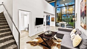 A spacious living area with a staircase, a flat-screen TV, a coffee table, and a sofa. - Elegant design meets optimal location amid the natural beauty of Downtown Redmond. (Redmond)