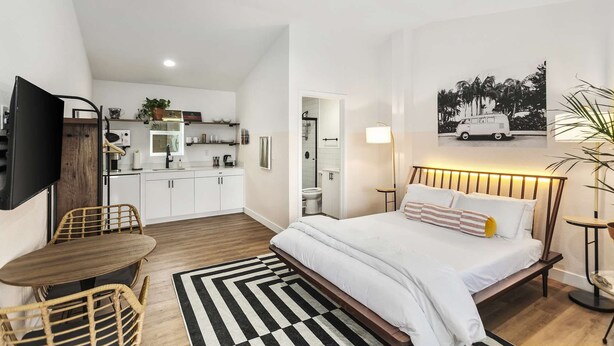 Un dormitorio moderno con una cama grande, una mesita de noche y vistas a una furgoneta a través de una ventana.