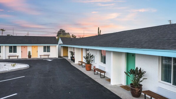 A motel with a parking lot and a row of rooms with individual entrances.
