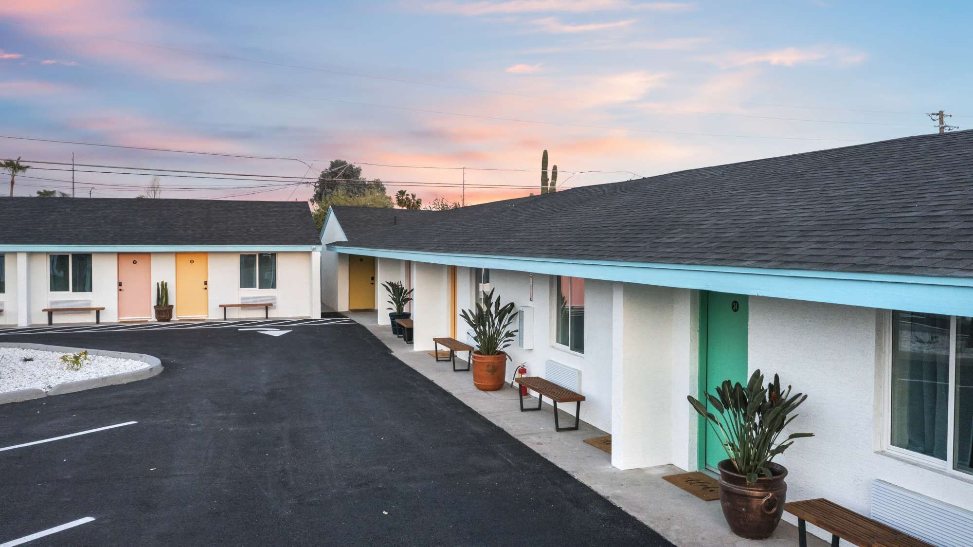 A motel with a parking lot and a row of rooms with individual entrances.