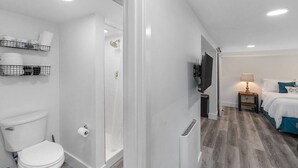 A bathroom with a toilet, shower, and storage shelves. - CC01 - Columbia City Urban Studio (Seattle)